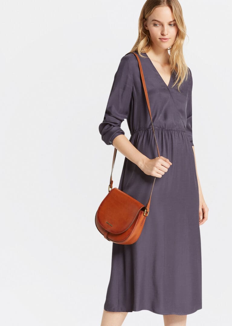 Woman modeling navy dress and leather crossbody bag