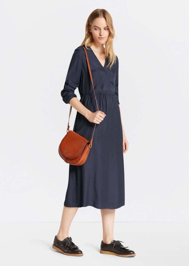 Woman in navy dress with brown leather bag