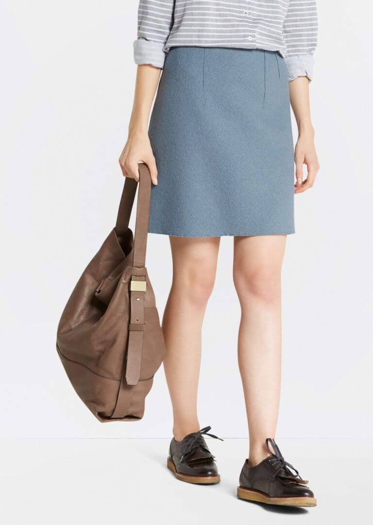 Woman holding brown bag wearing blue skirt and shoes