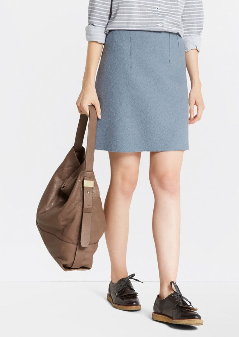 Woman holding brown bag, wearing blue skirt and shoes