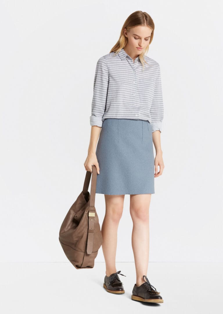 Woman in striped shirt and blue skirt with bag