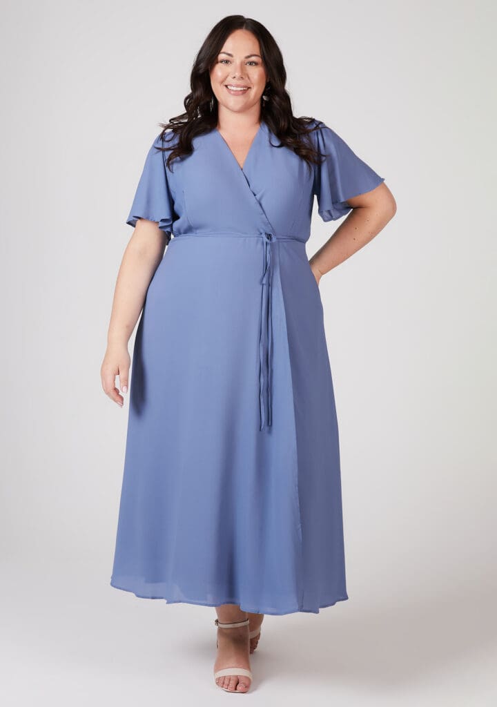 Woman in blue wrap dress smiling confidently