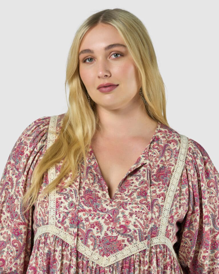 Blonde woman in floral dress posing for portrait.