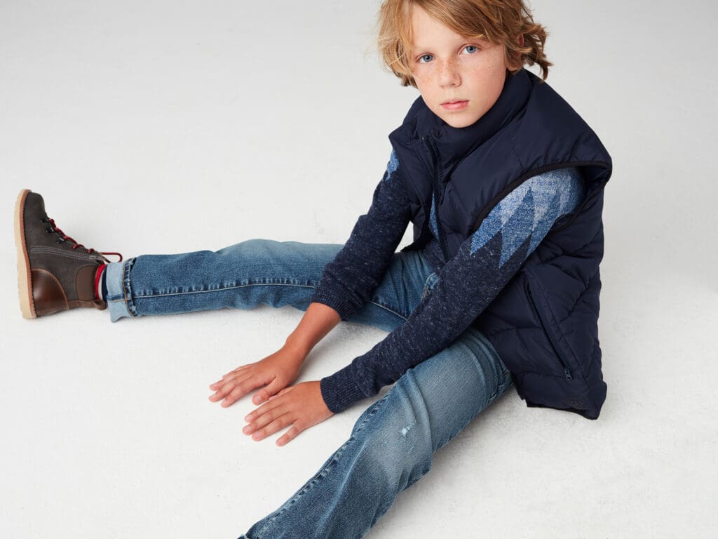 Young boy in puffer jacket and jeans sitting