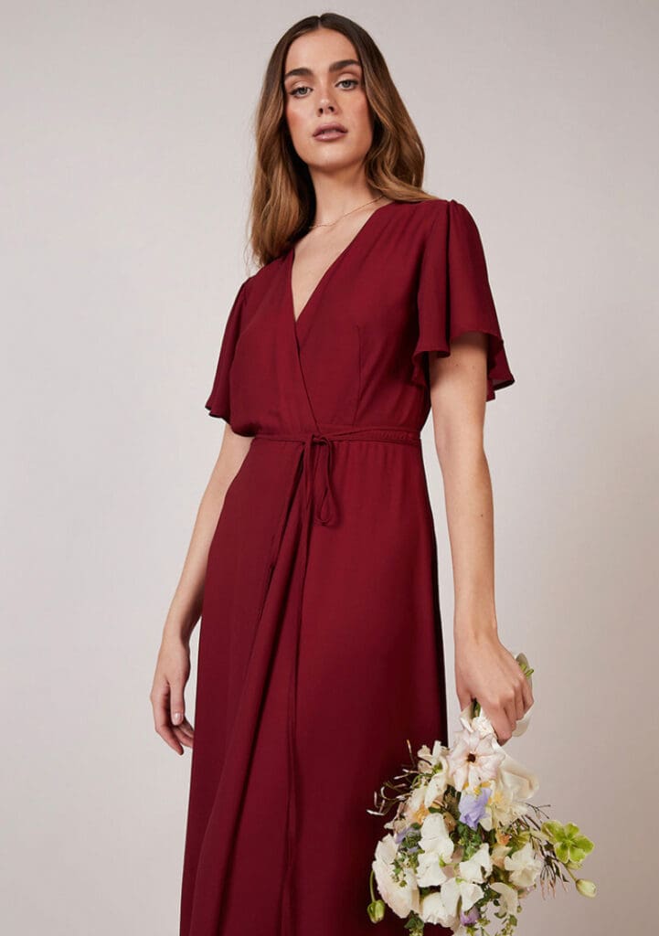 Woman in burgundy dress holding bouquet of flowers